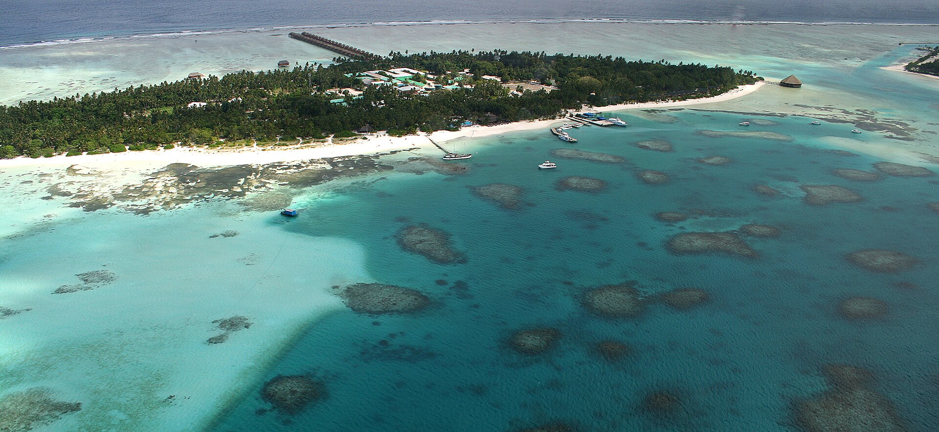 Aerial view of a Maldives resort island, lagoon and overwater villas